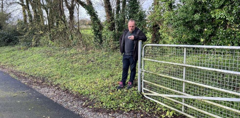 Dan leans against the post of an open metal gate.