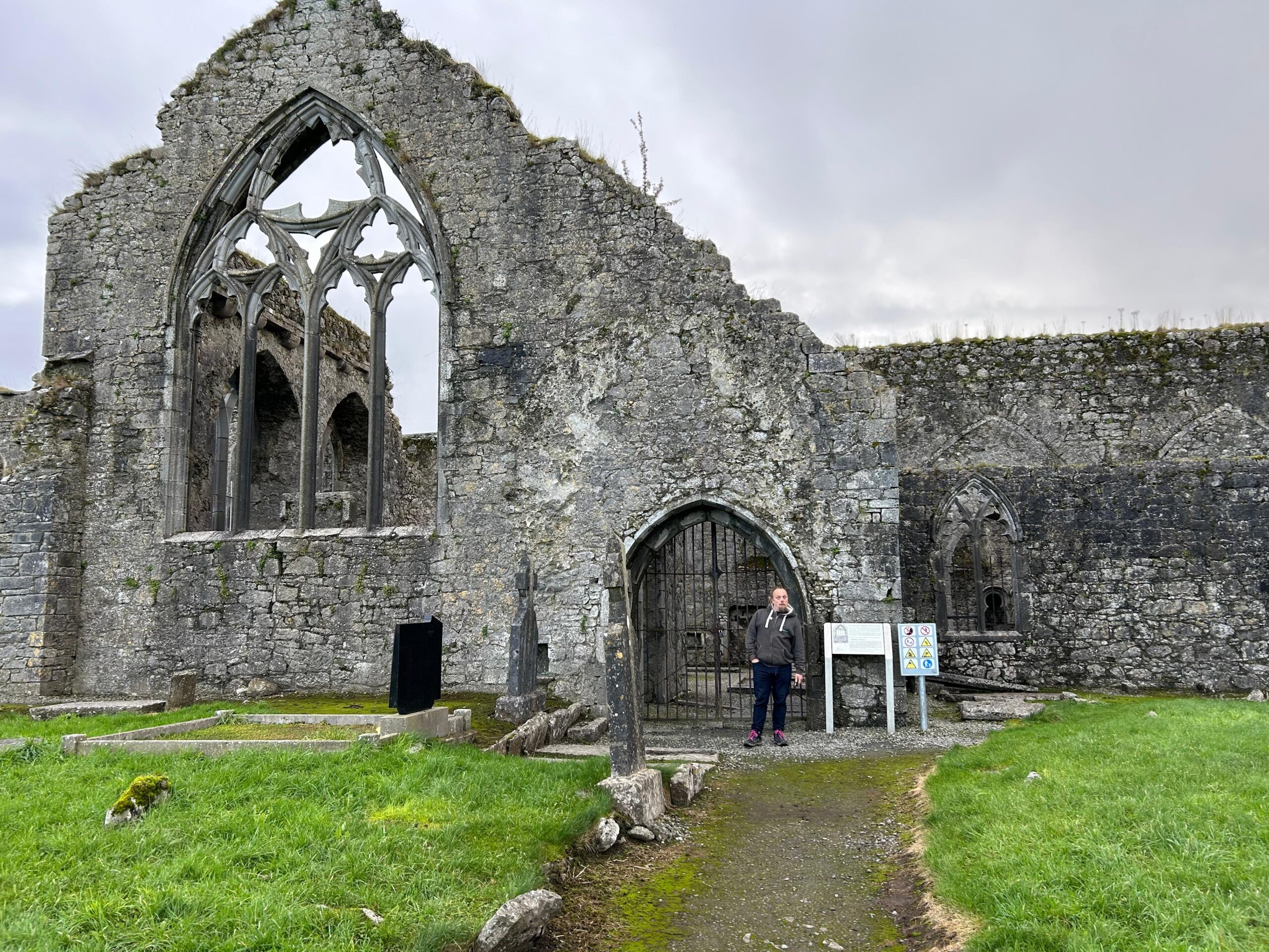 Full image of Dan stands in front of a ruined priory.
