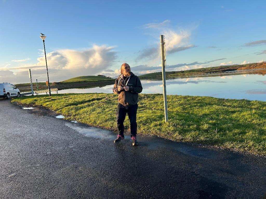 Full image of Dan stands near the sea.