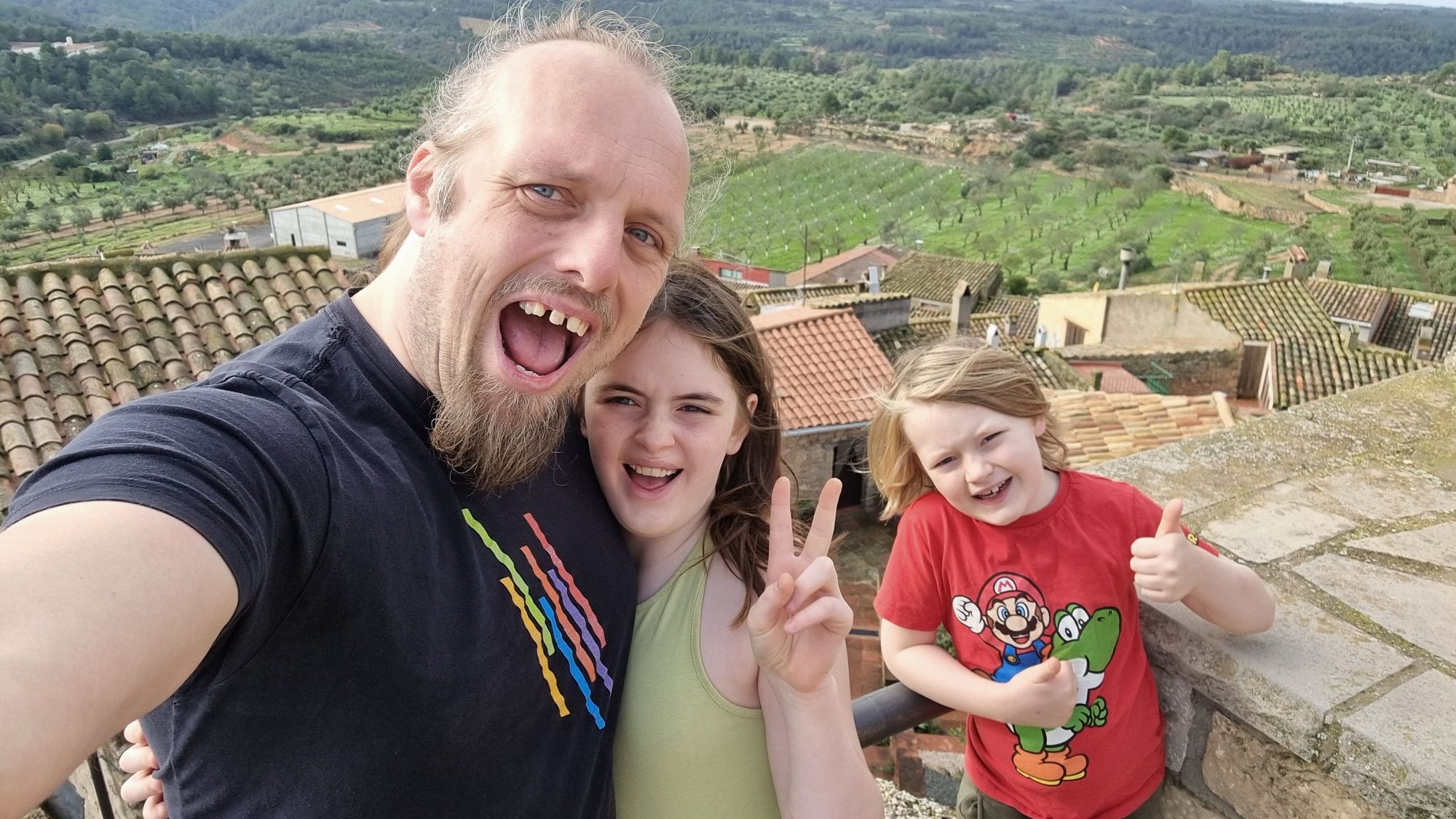 Full image of Dan and two kids look excited atop a castle in rural Catalonia.