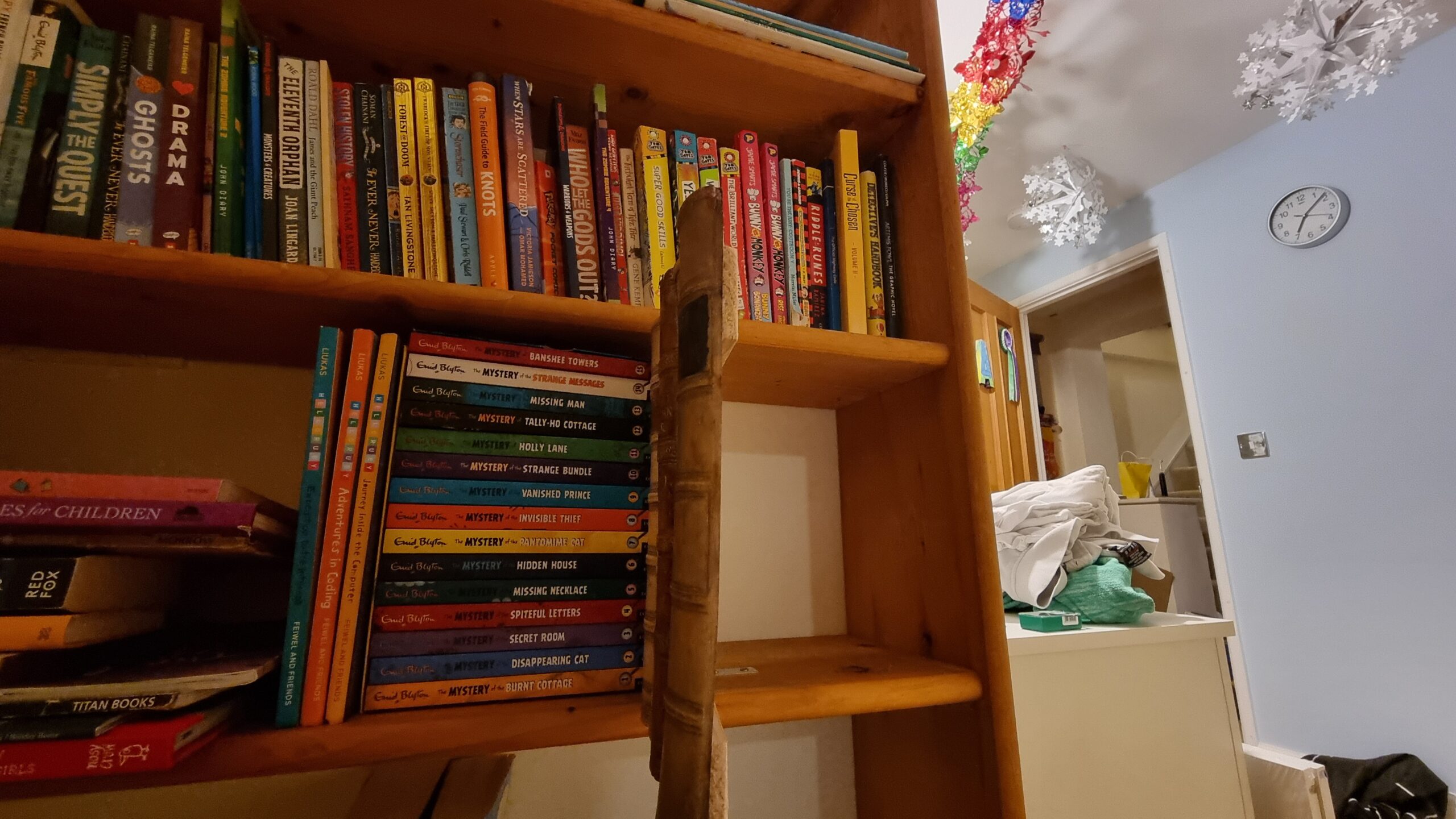 Full image of The same bookshelf, but now with the older books - actually fake fronts - swung open to reveal an empty cabinet behind.