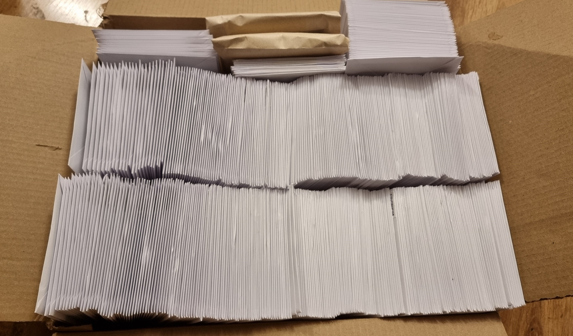 Full image of Cardboard box containing many hundreds of sealed Christmas-card-sized envelopes.