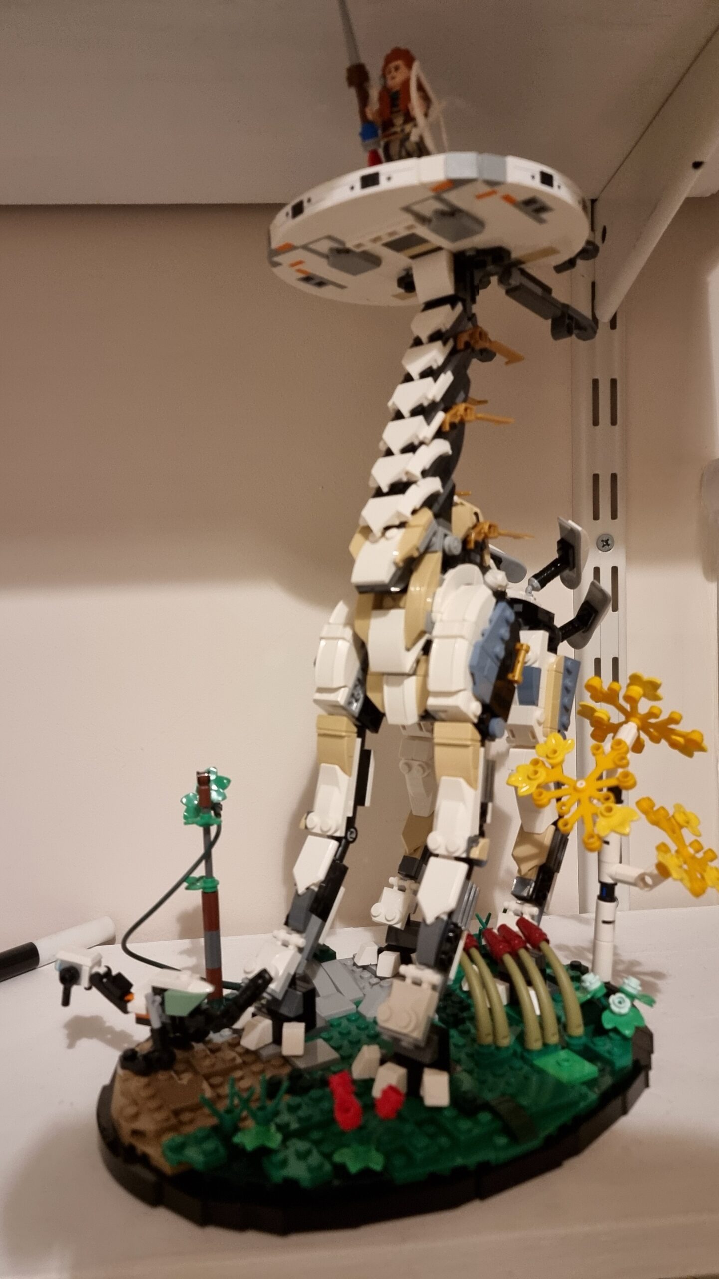 Full image of Lego model of a Tallneck from videogame Horizon: Zero Dawn/Forbidden West, with minifigure of protagonist Aloy standing atop its head.