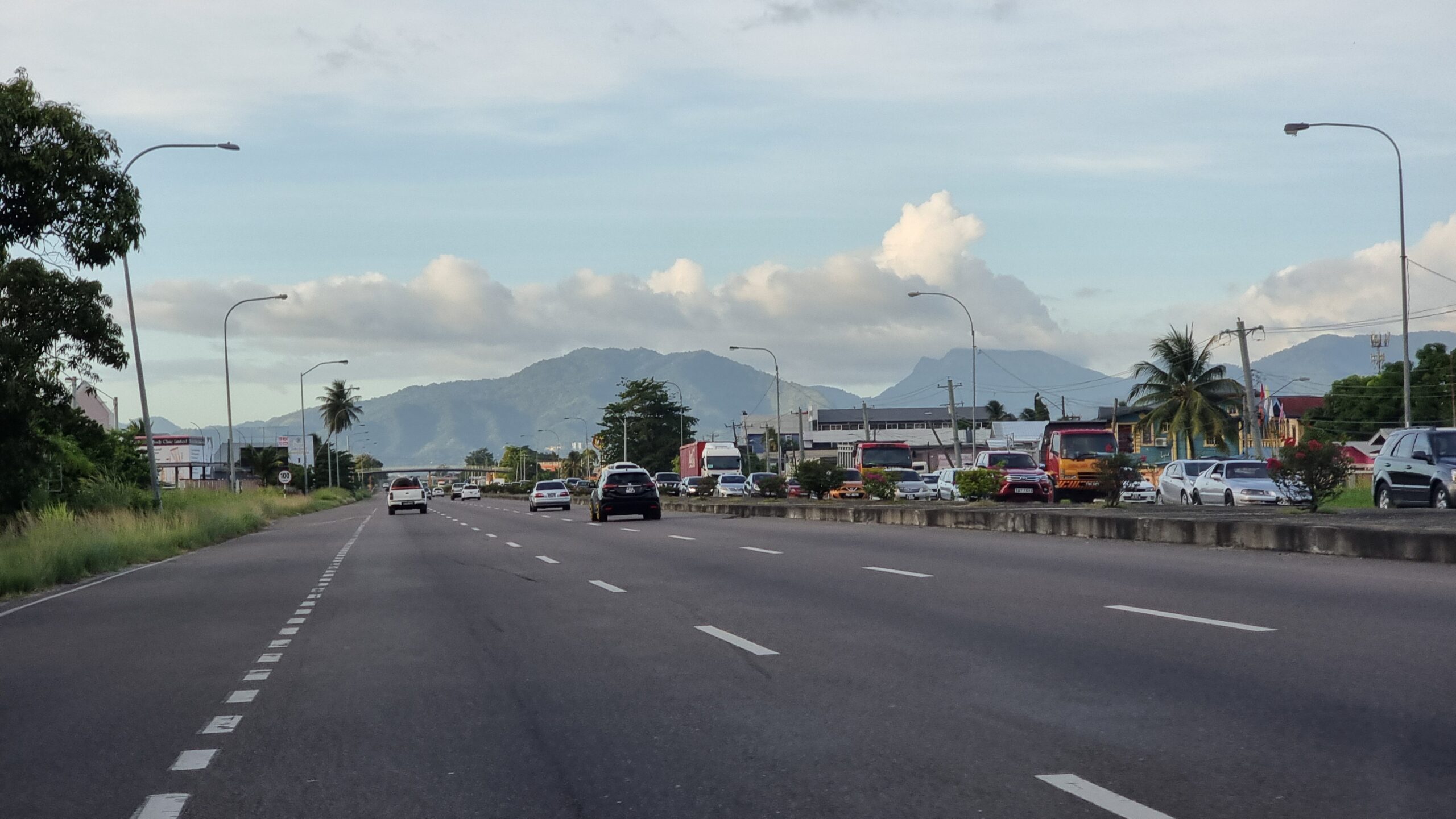 Full image of Six-lane highway as viewed through a windscreen. Traffic ahead is flowing well but there's a jam underway on the opposite carriageway.