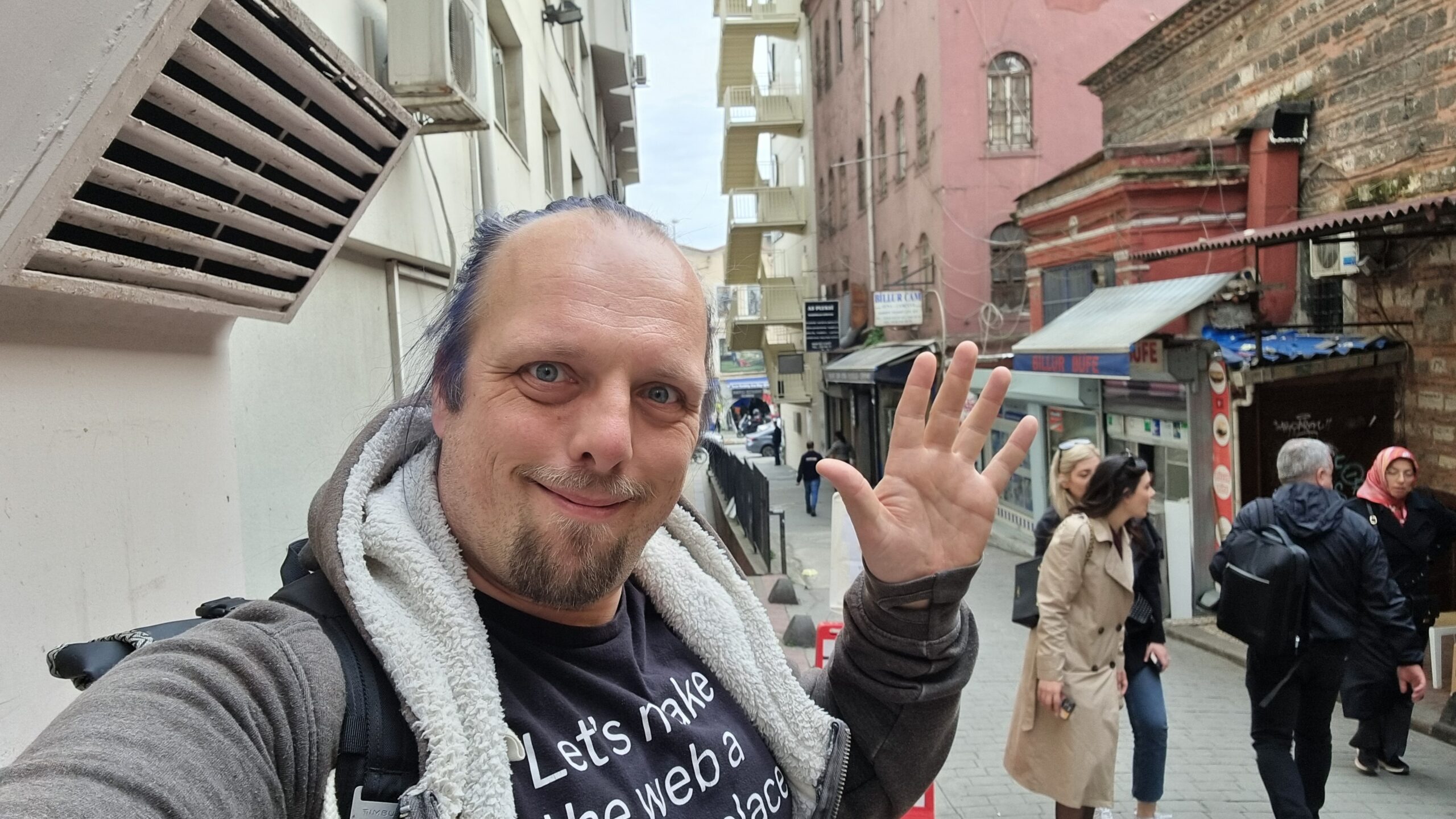 Full image of Dan waves from a narrow but busy Istanbul city street.