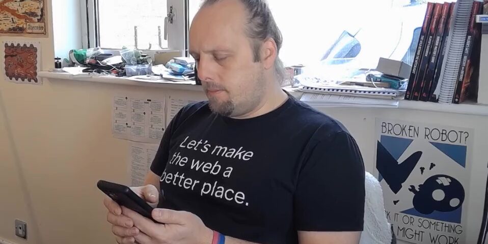 Dan, sitting in an office, staring at his phone... as if he were on his phone.