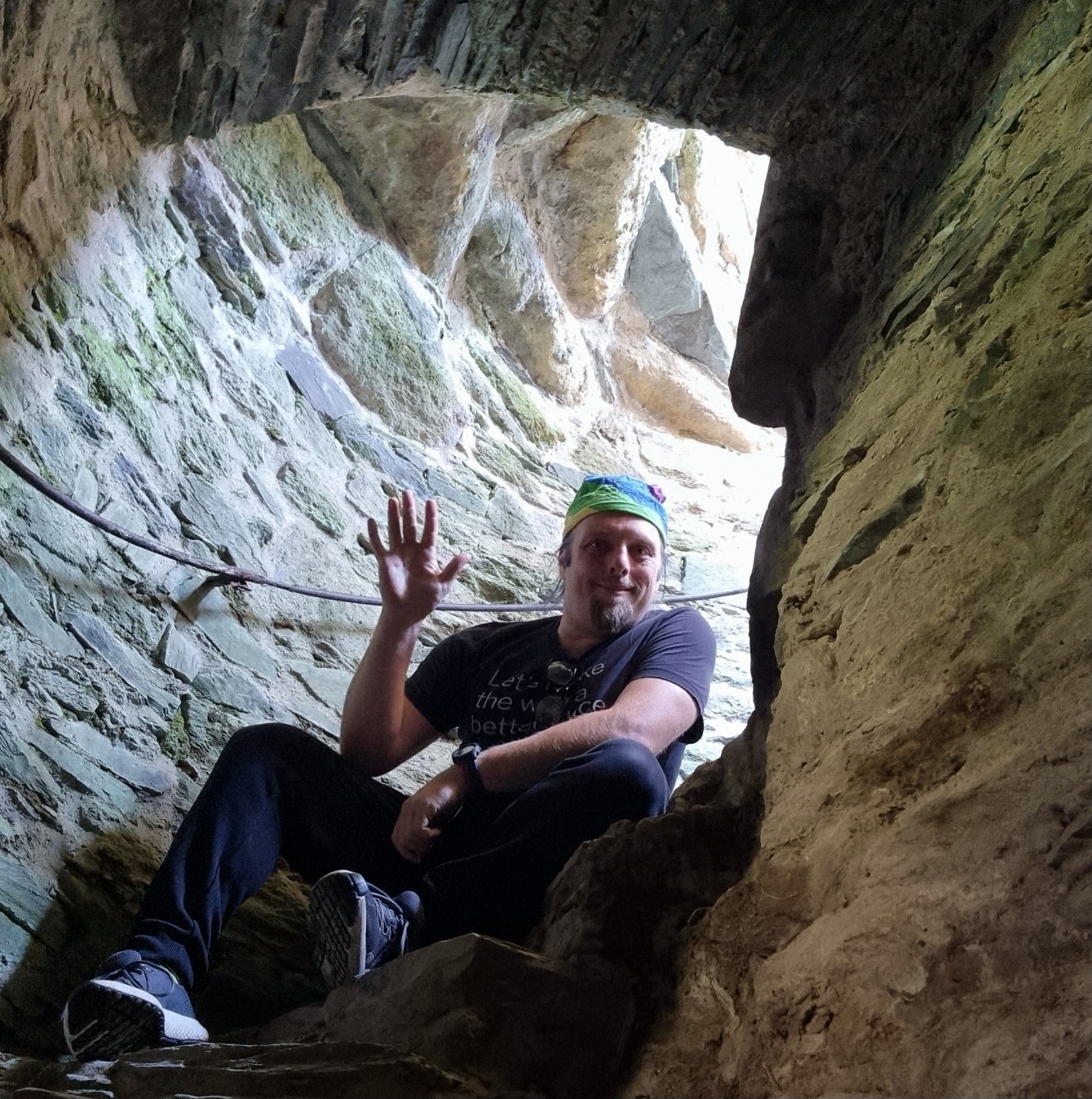 Full image of Dan crouches on a stone spiral staircase.