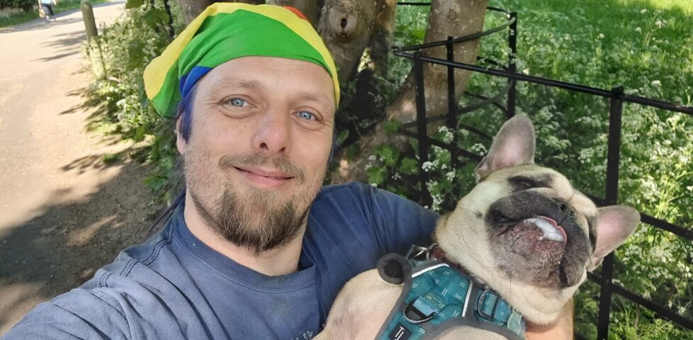 Dan carries a French Bulldog along a rural lane.