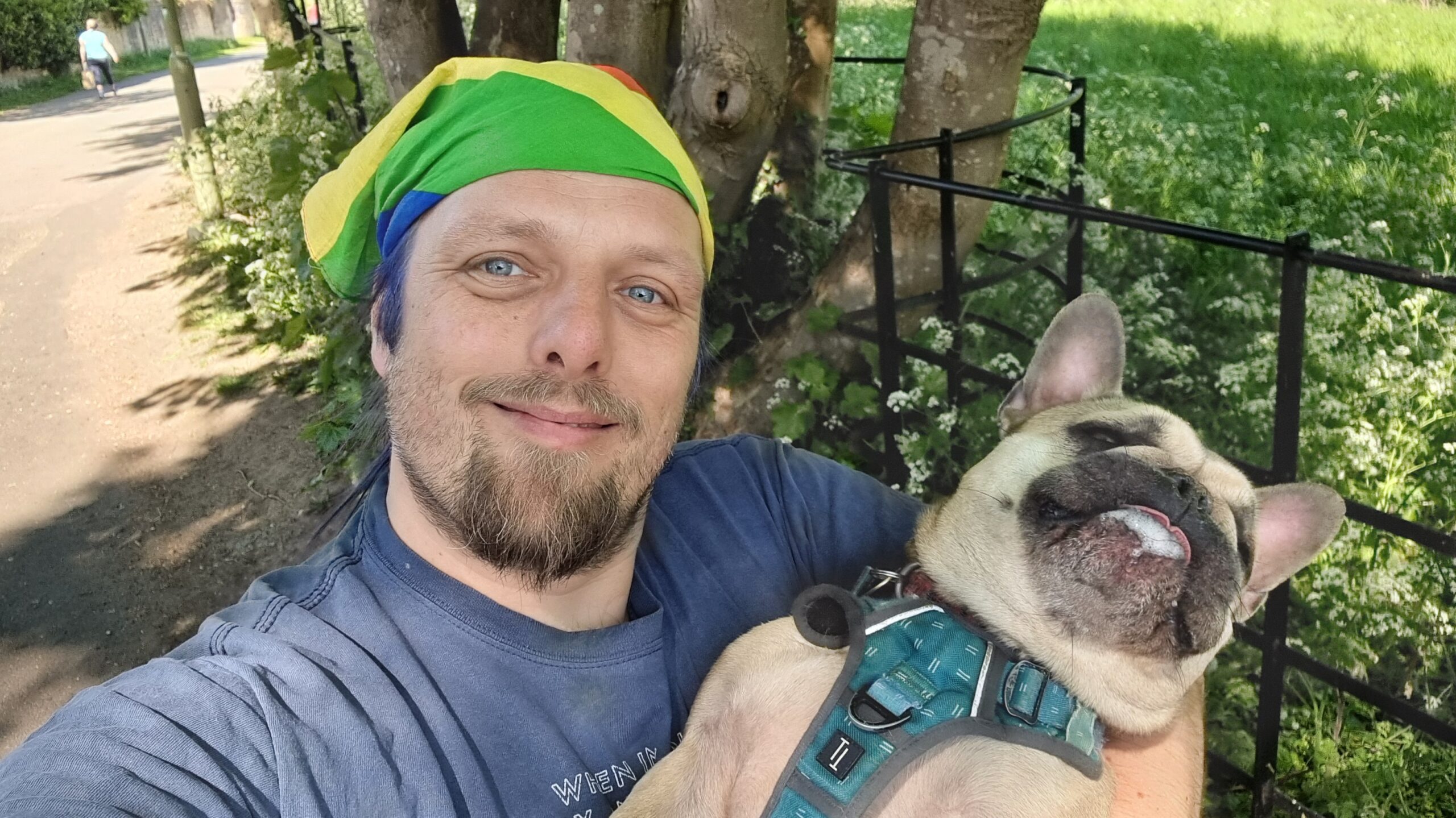 Full image of Dan carries a French Bulldog along a rural lane.