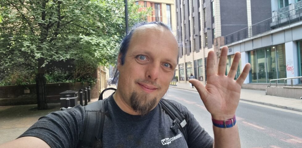 Dan waves from a leafy urban street.