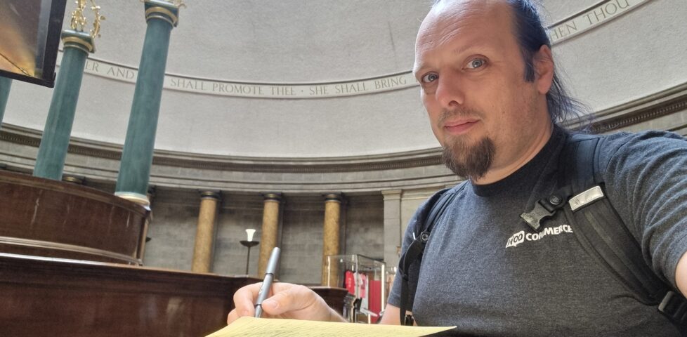 Sitting in a traditionally-decorated circular reading room, Dan writes in a notepad.