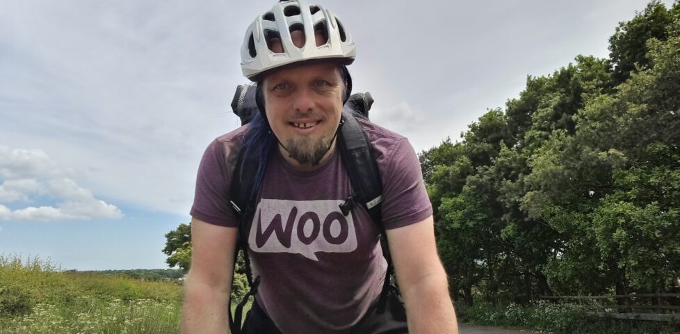 Leaning hard into his handlebars, Dan cycles up to the top of a rural hill.