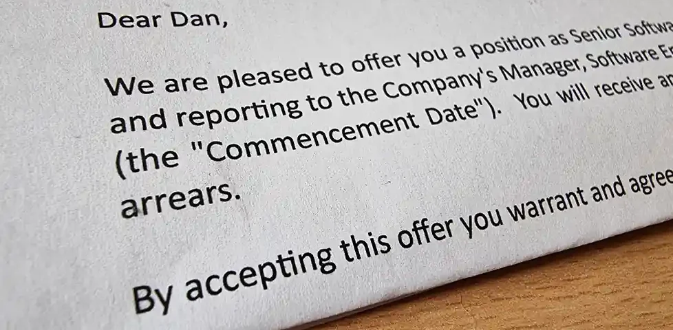 Close-up of part of a letter, the visible part of which reads: Dear Dan, We are pleased to offer you a position as Senior Softwa... / and reporting to the Company's Manager, Software E... / (the "Commencement Date"). You will receive an... / By accepting this offer you warrant and agree...