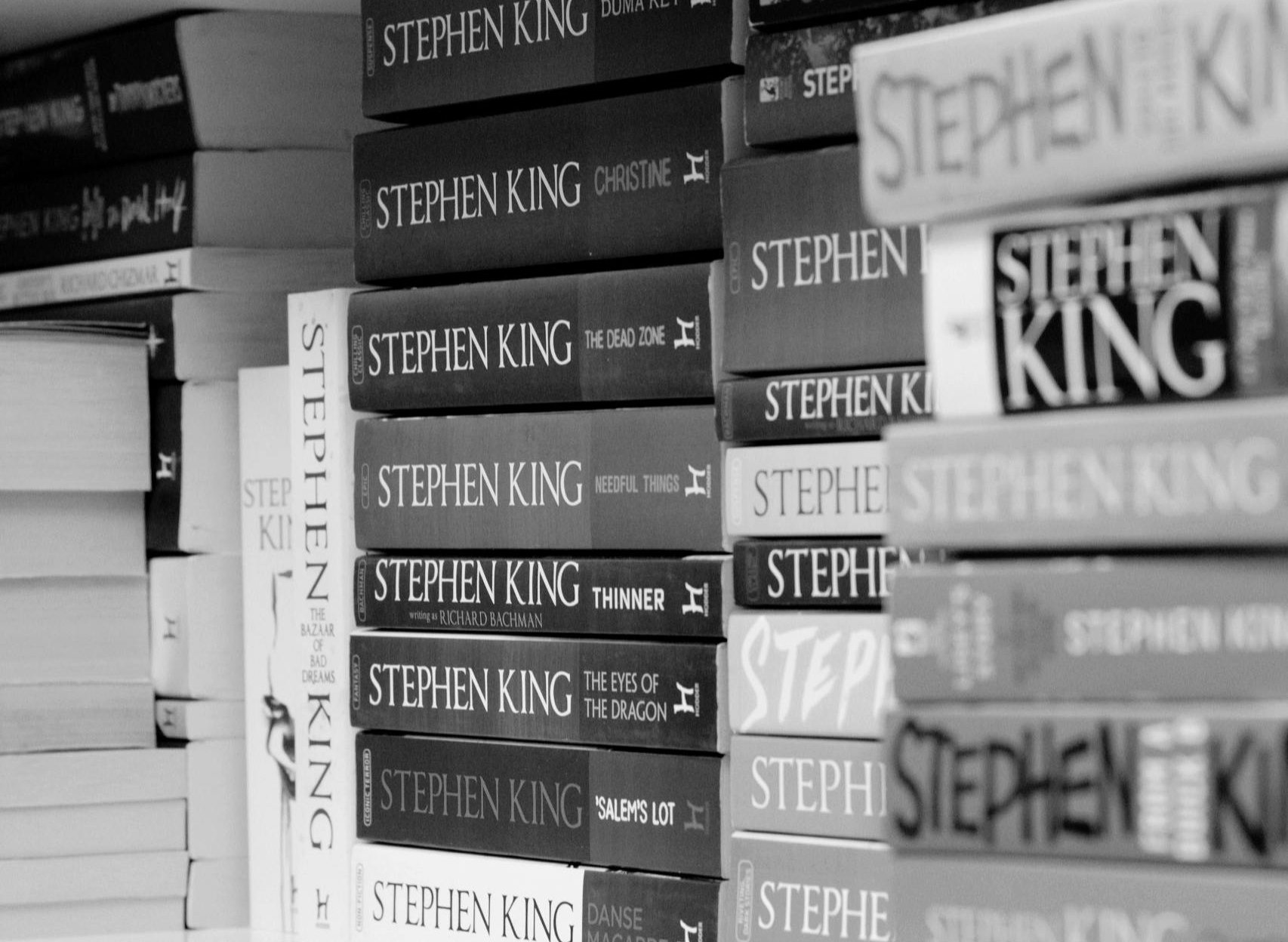 Full image of Monochrome photograph showing a shelf packed full of Stephen King's novels.