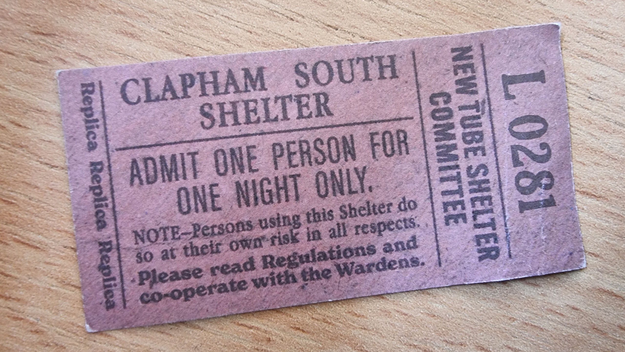 Full image of Small pink replica ticket reading 'Clapham South Shelter: Admit One Person for One Night Only', ticket number L0281.