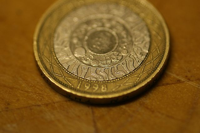 Close-up of a 1998 £2 coin; bimetallic, with an inner ring of cogs expanding outwards into several interlocking spirals.