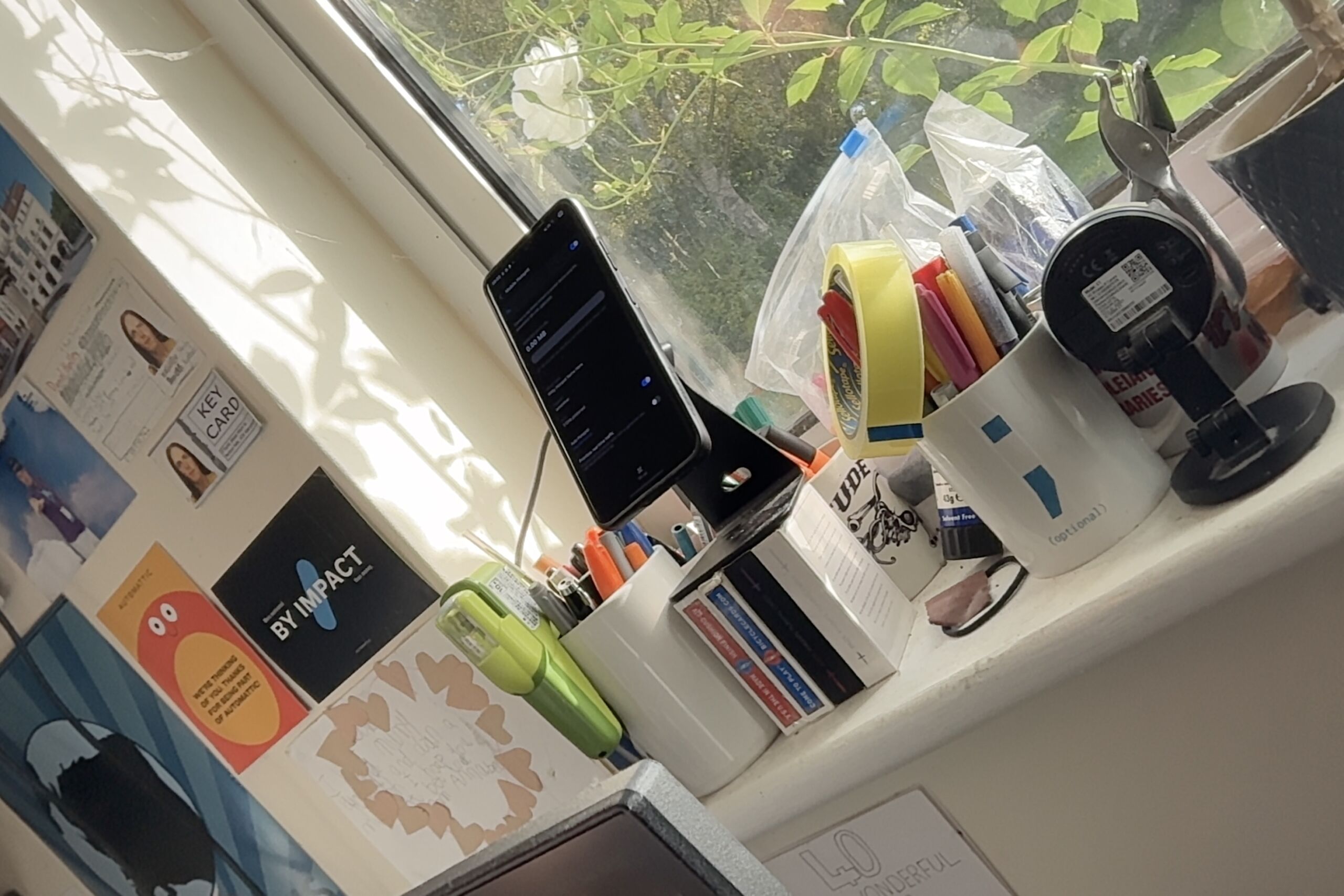 Full image of A phone, displaying a tethering configuration screen, is propped on top of several decks of cards on a cluttered window ledge.