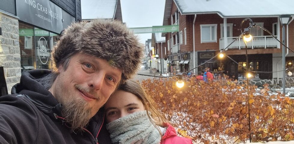 Wrapped up in warm hats and scarves, Dan and a tweenage girl stand in the snowy street of a Lapland town.