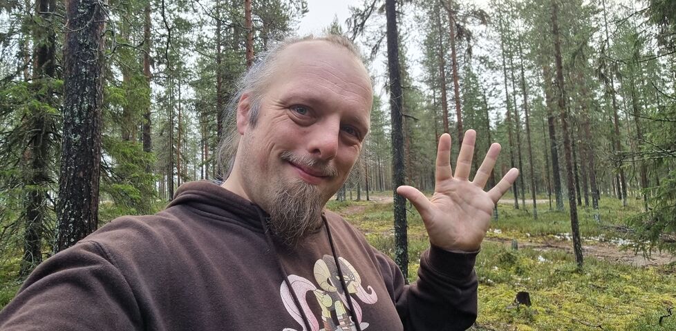 In a spruce forest, Dan waves.