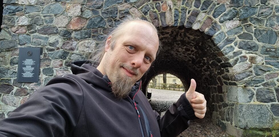 Dan throws a thumbs up outside a sea fort gateway.