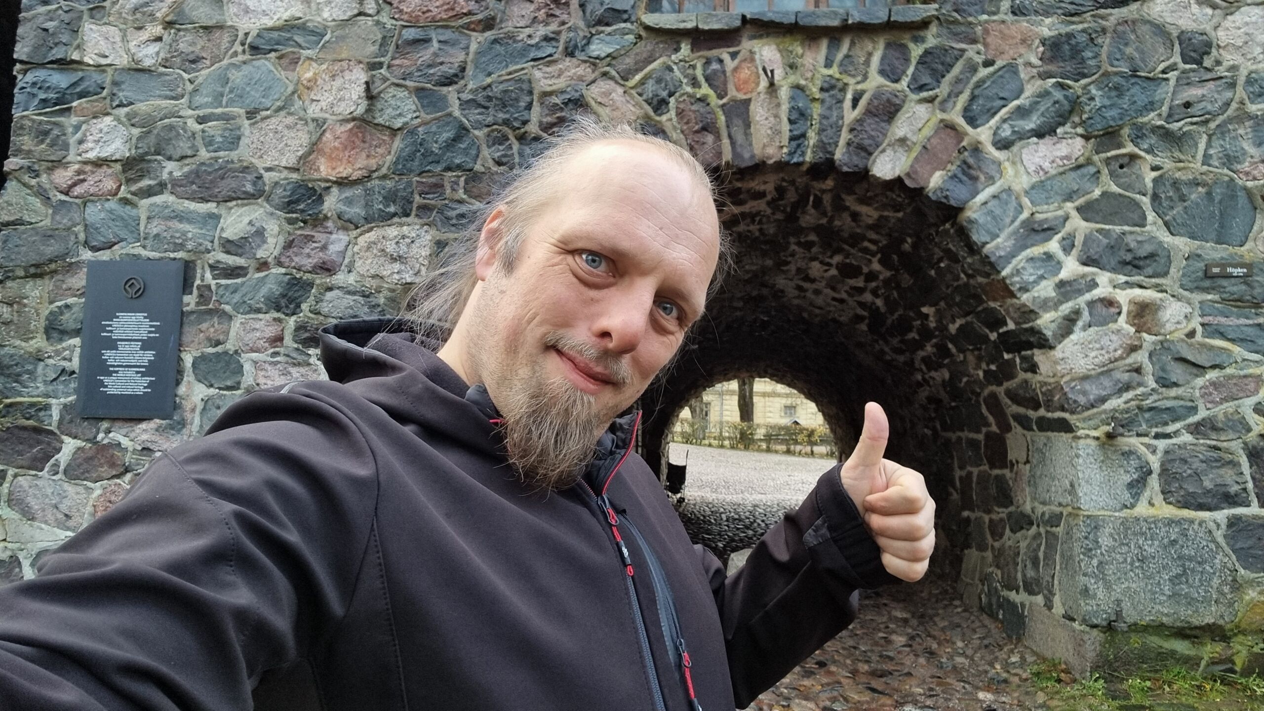 Full image of Dan throws a thumbs up outside a sea fort gateway.