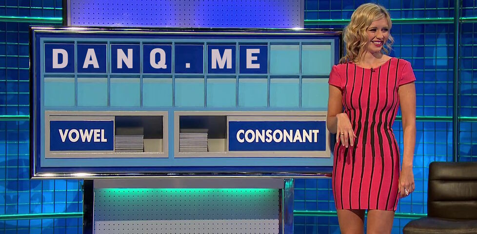 Rachel Riley, wearing a pink and black dress, stands in front of a partially-filled Countdown board showing the letters 'DANQ.ME'.