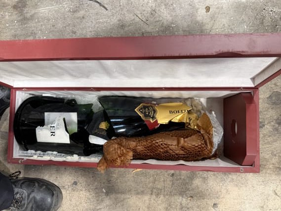 A wooden case containing a completely smashed 6-litre champagne bottle.