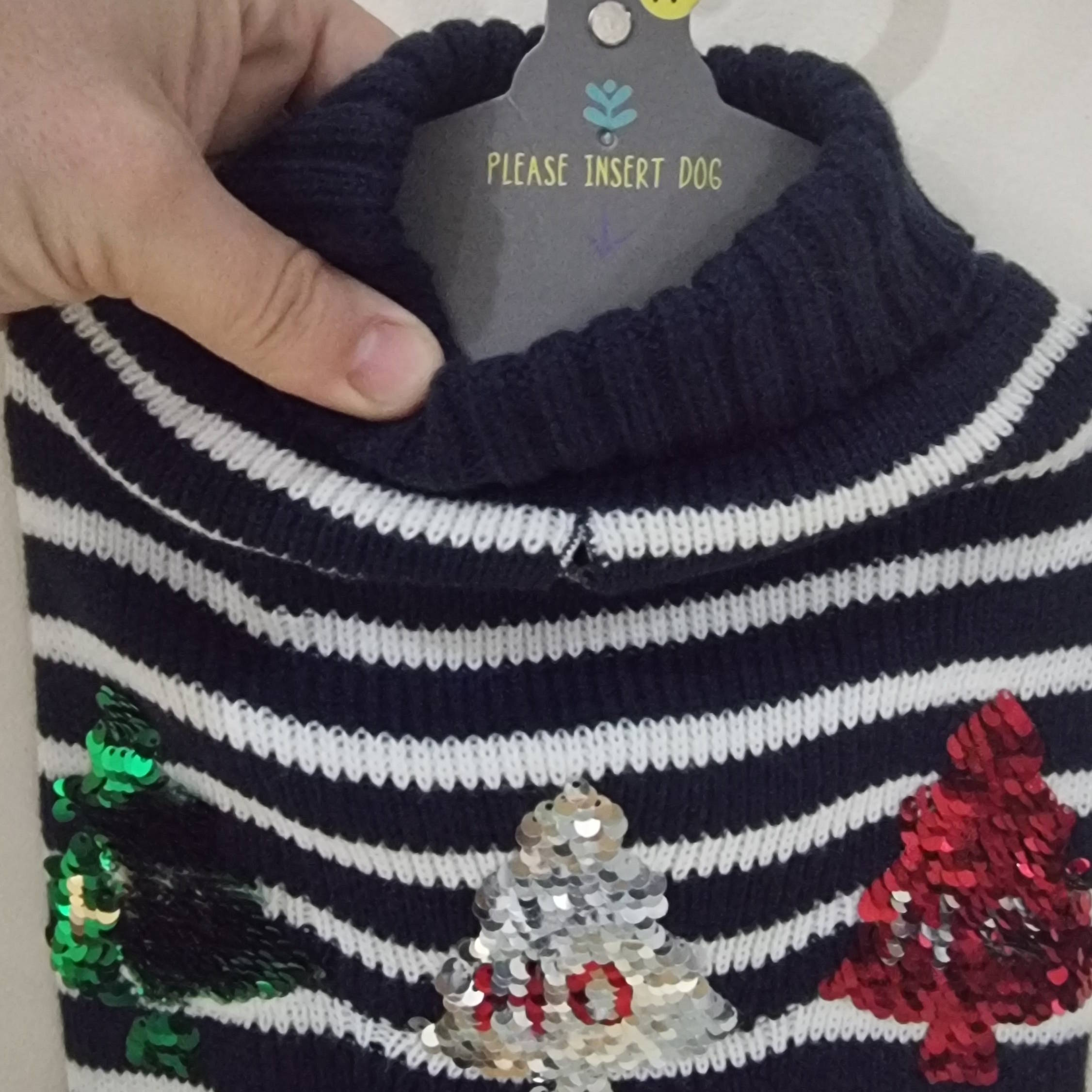 Full image of Christmas jumper for a dog, featuring blue-and-white stripes and sequin Christmas trees; its hanger contains an arrow pointing down alongside the text 'please insert dog'.