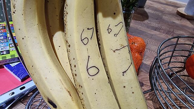 Close up of a bunch of bananas. The numbers 6 and 7 have been drawn on them in ball point pen.