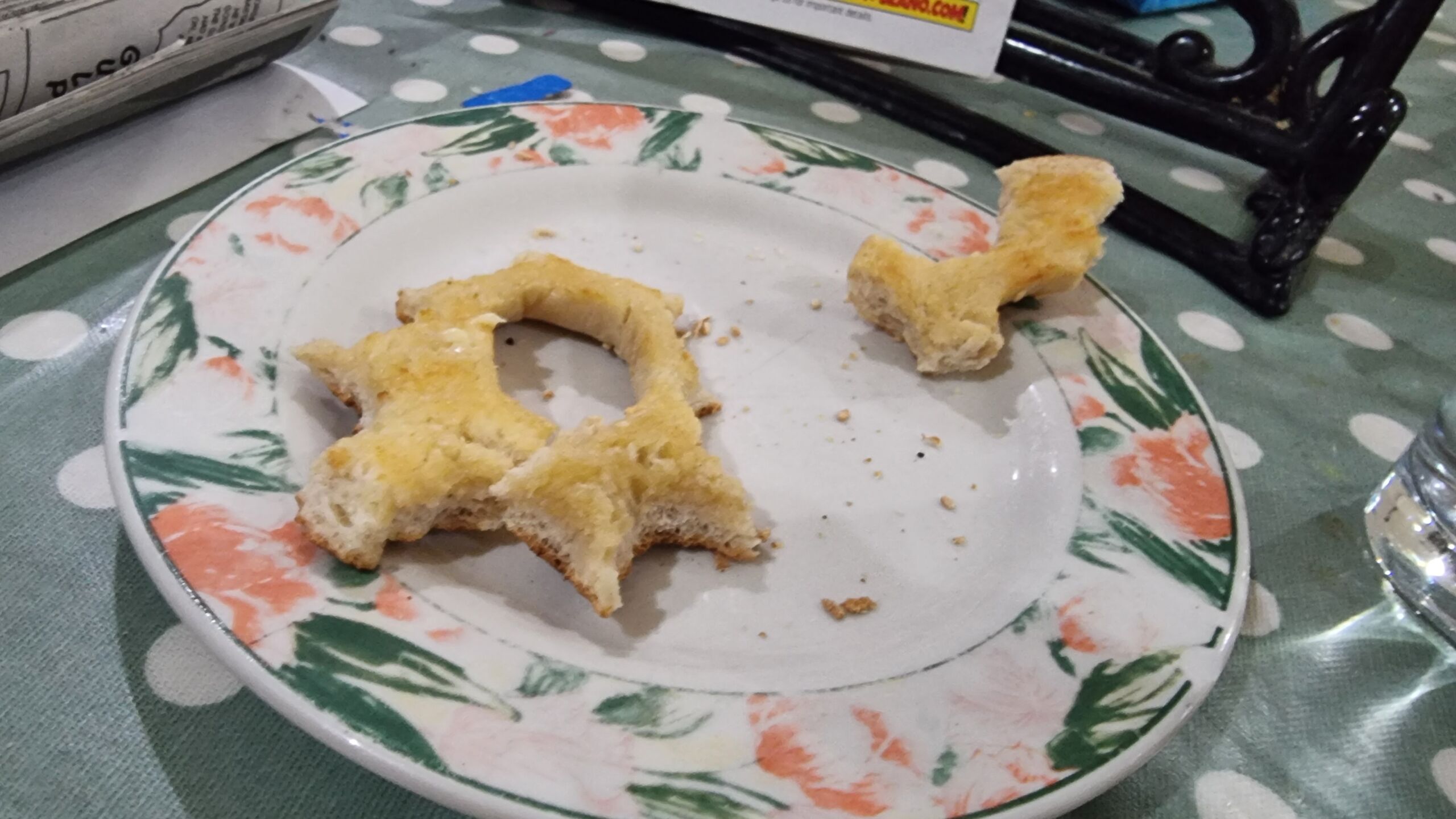 Full image of On a plate, buttered bagel has been nibbled all around the outside, leaving only the hole surrounded in a thin circle of bread.