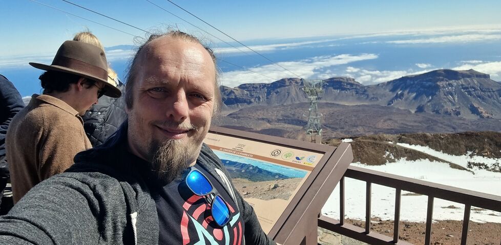 Dan stands by an information board in front of a broad volcanic crater.