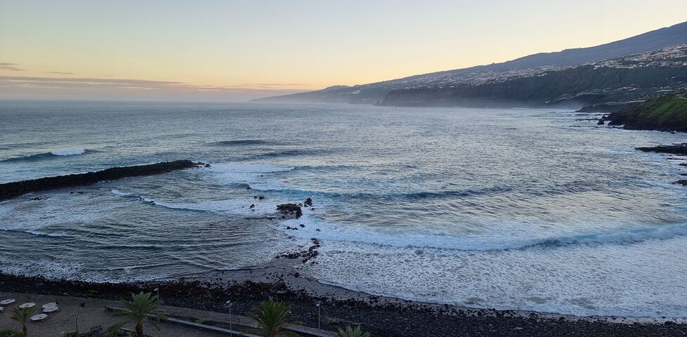 View of waves crashing into a bay on a rugged island coastline.