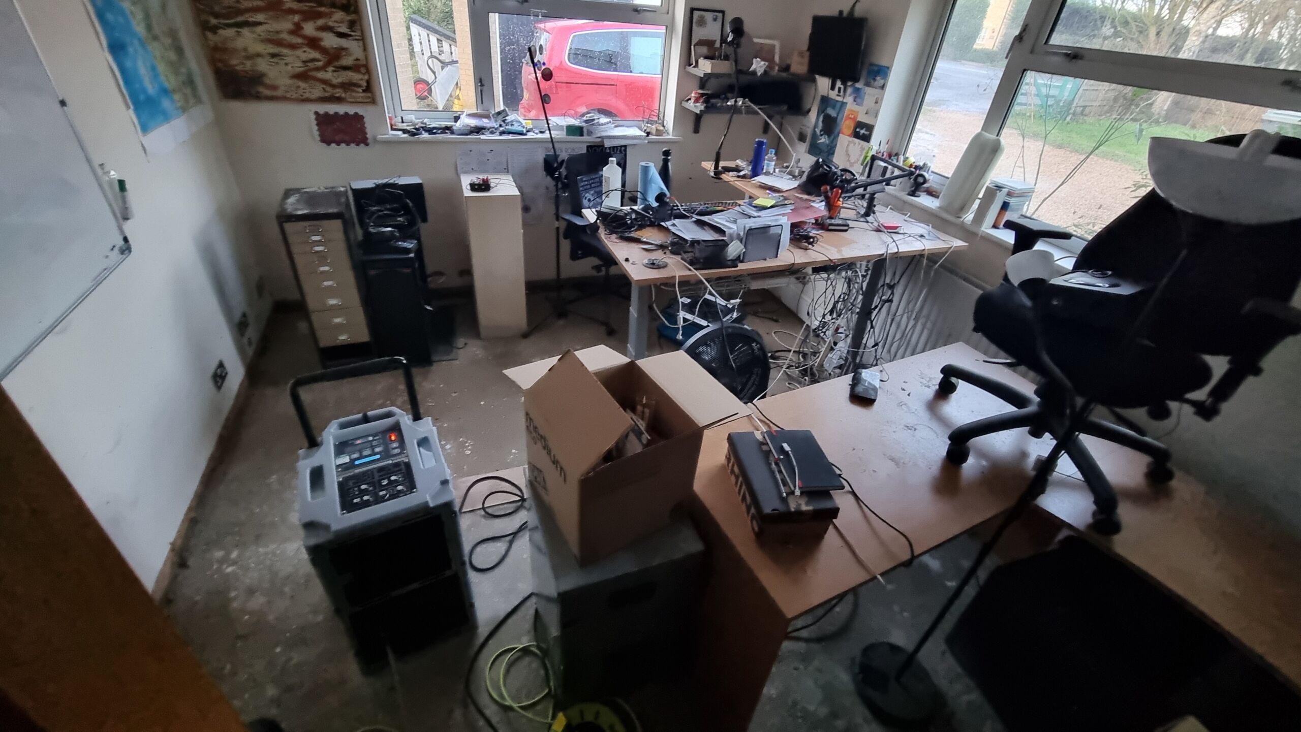 Full image of A home office with its floor stripped down to poured concrete and an industrial dehumidifier running.