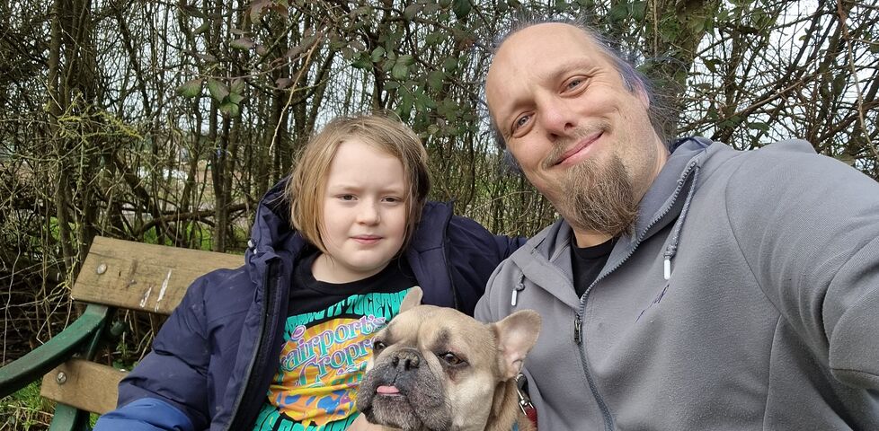 Dan sits with a young boy and a French Bulldog.