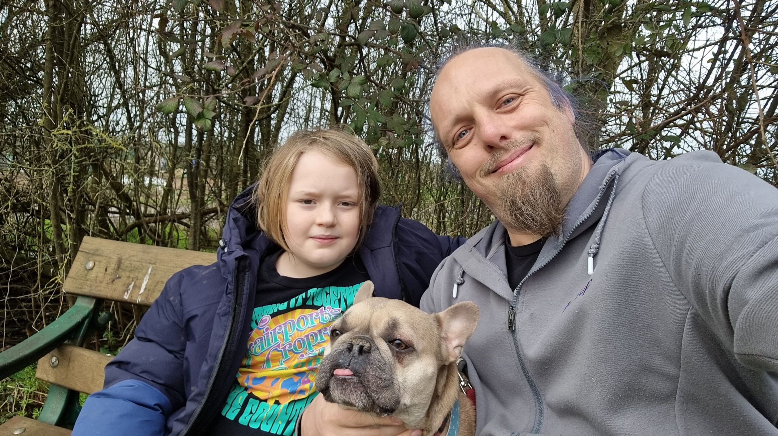 Full image of Dan sits with a young boy and a French Bulldog.