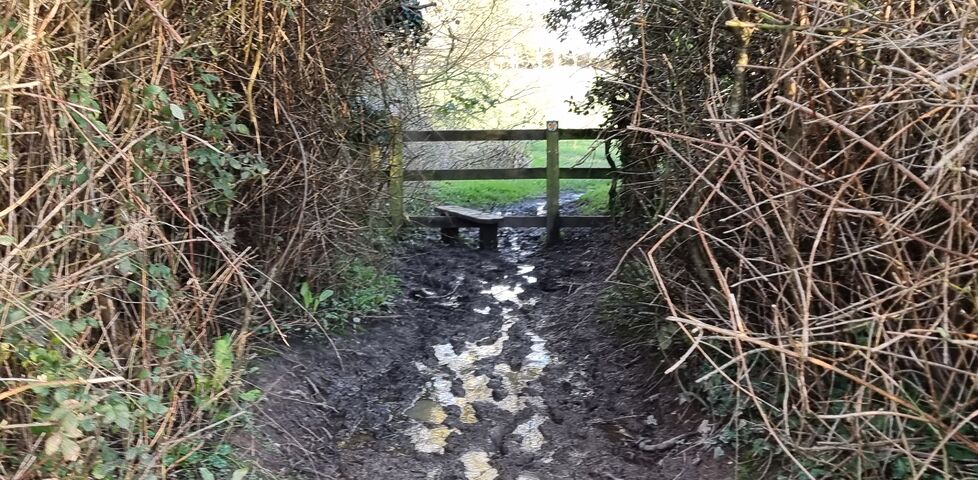 An extremely muddy footpath leading to a stile.