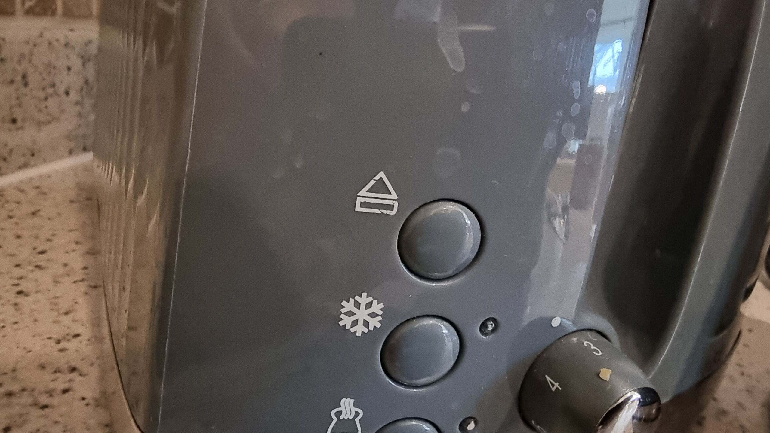 Full image of Close up of the side of a toaster, showing an "eject" button (rectangle with an upward-pointing triangle above it).