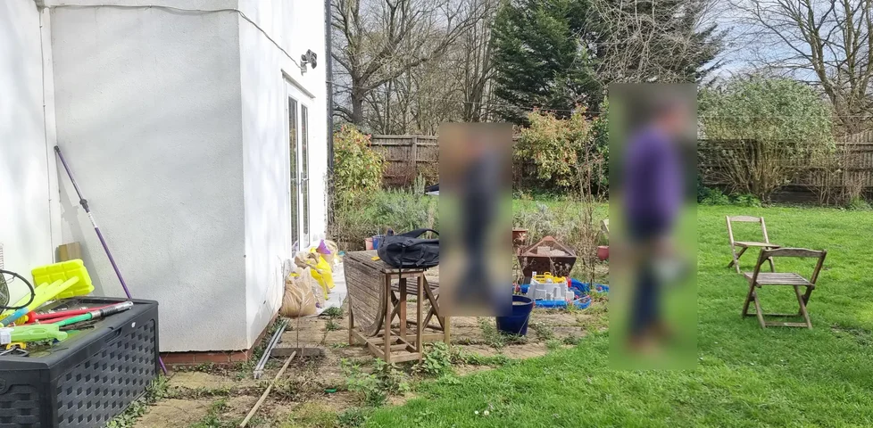 Two white men look at the outside of a sandbag-protected house.