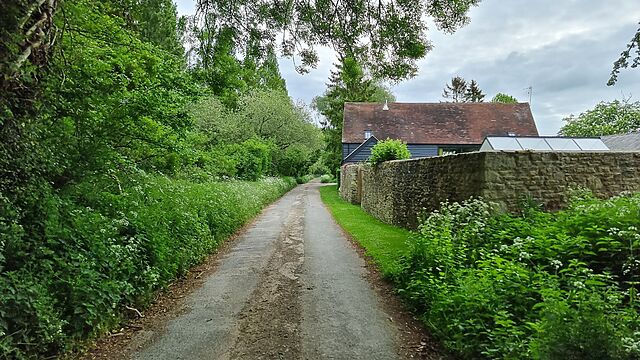 A paved lane leading past a farmhouse.