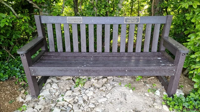 A memorial bench with two distinct plaques on it.