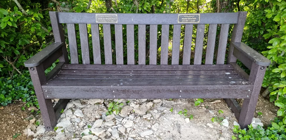 A memorial bench with two distinct plaques on it.