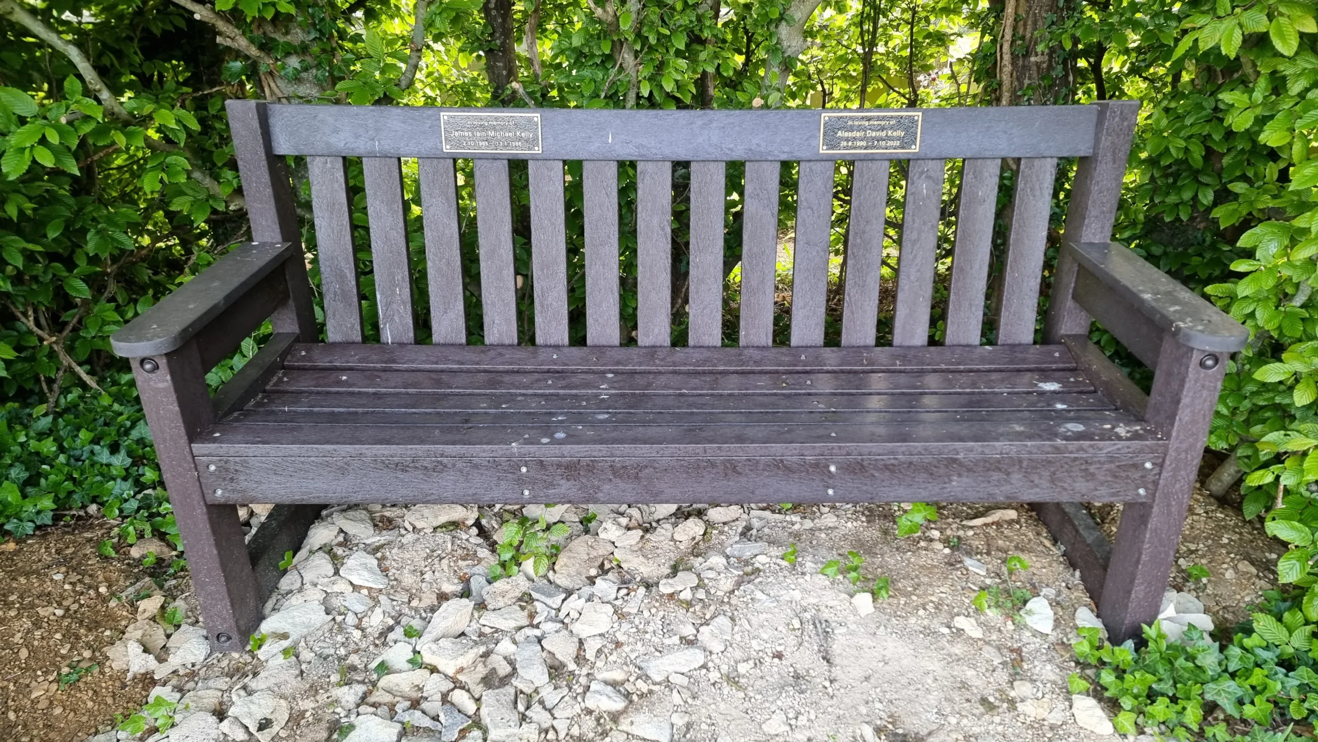 Full image of A memorial bench with two distinct plaques on it.