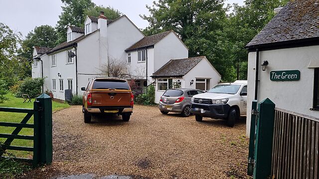 Several vehicles parked in the rain on the rural residential driveway of 'The Green'.