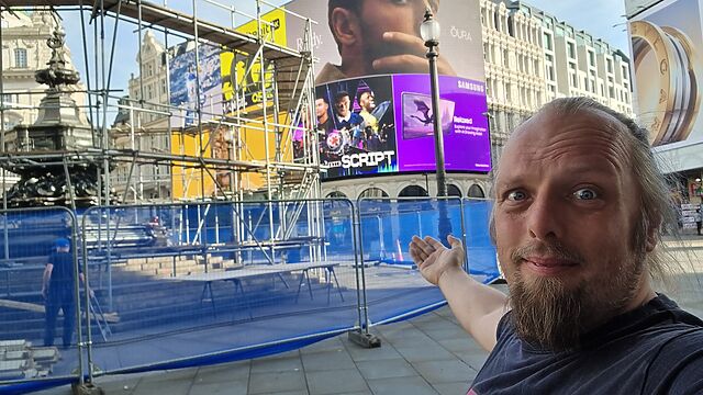 Dan stands in front of a scaffolded fountain at the iconic Piccadilly Circus.