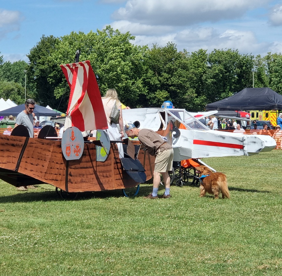 Full image of A cardboard longship collides with an X wing in a grassy field.