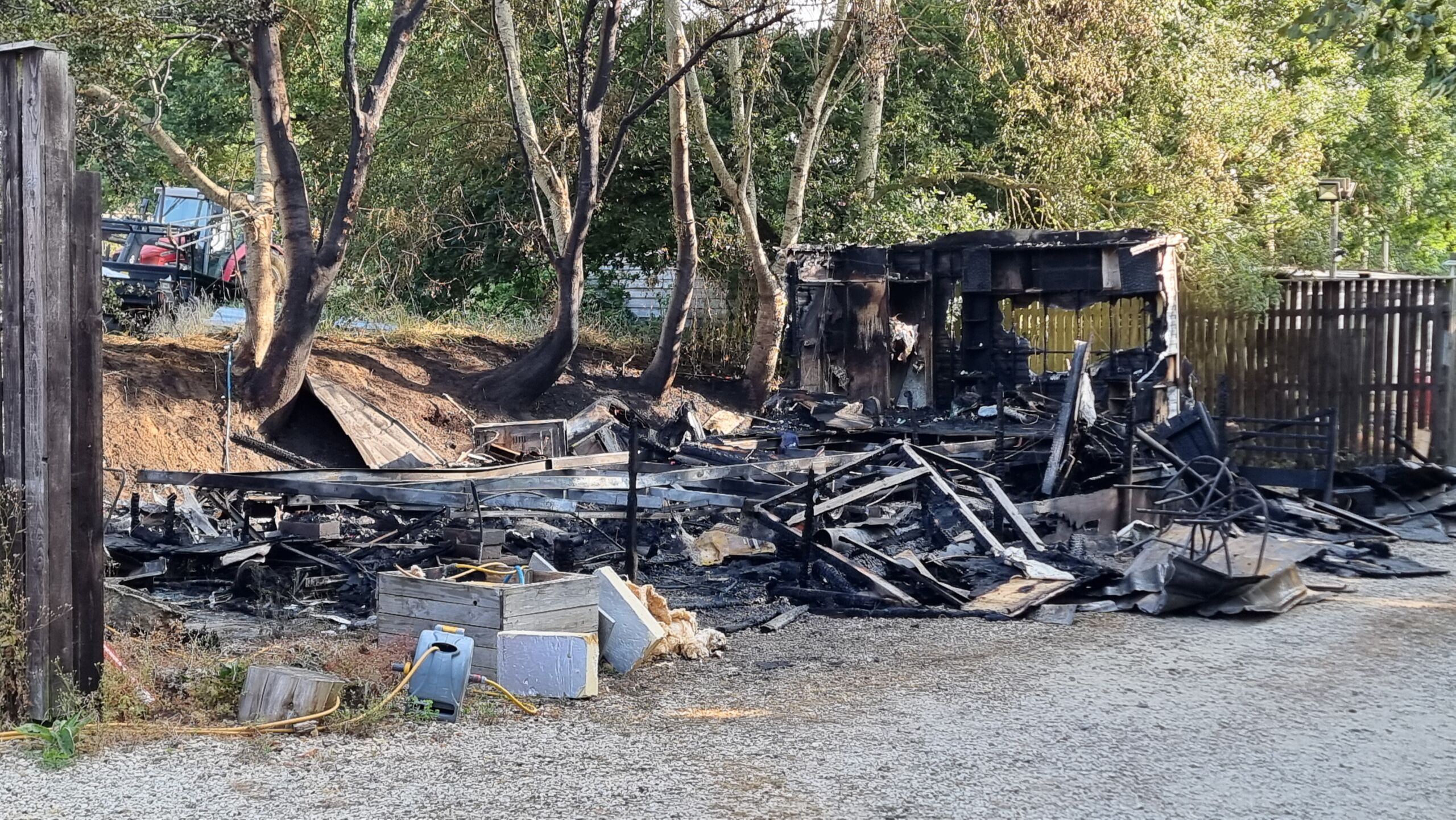 Full image of A handful of metal frame struts stick out from an ash pile that was clearly once a static caravan.