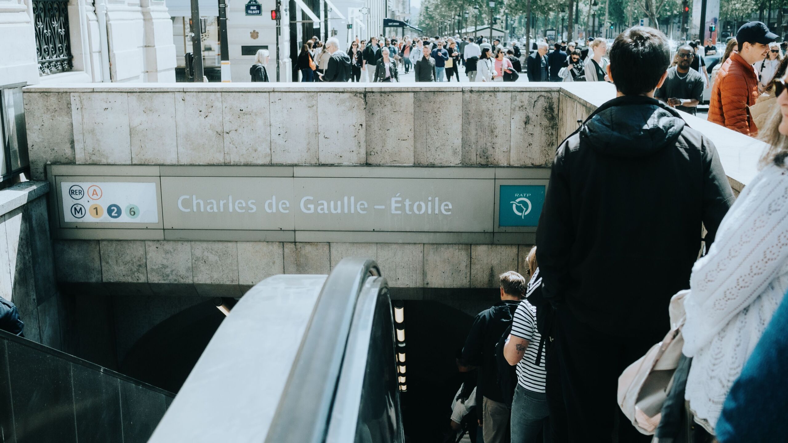 Full image of Crowds file down the escalator into Charles de Gaulle-Étoile station.