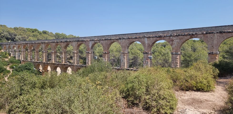 A Roman aquaduct spans a forested valley. 