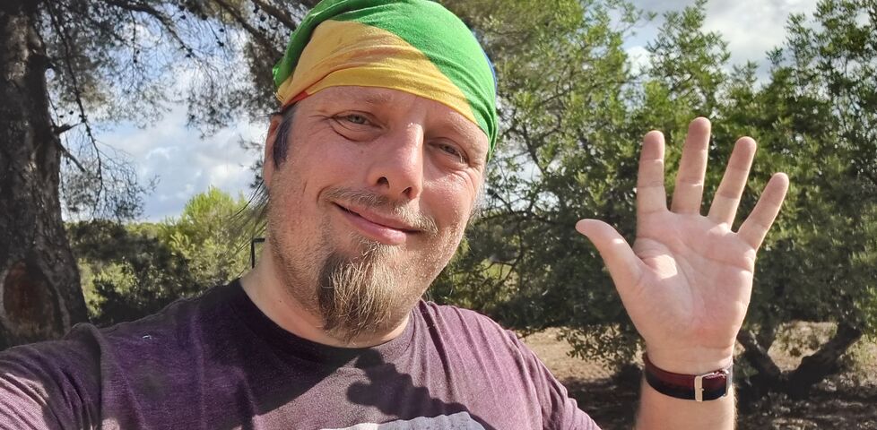 Dan waves in a bright forest.