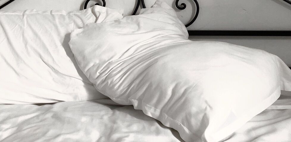 Two crumpled pillows at the head of a double bed.
